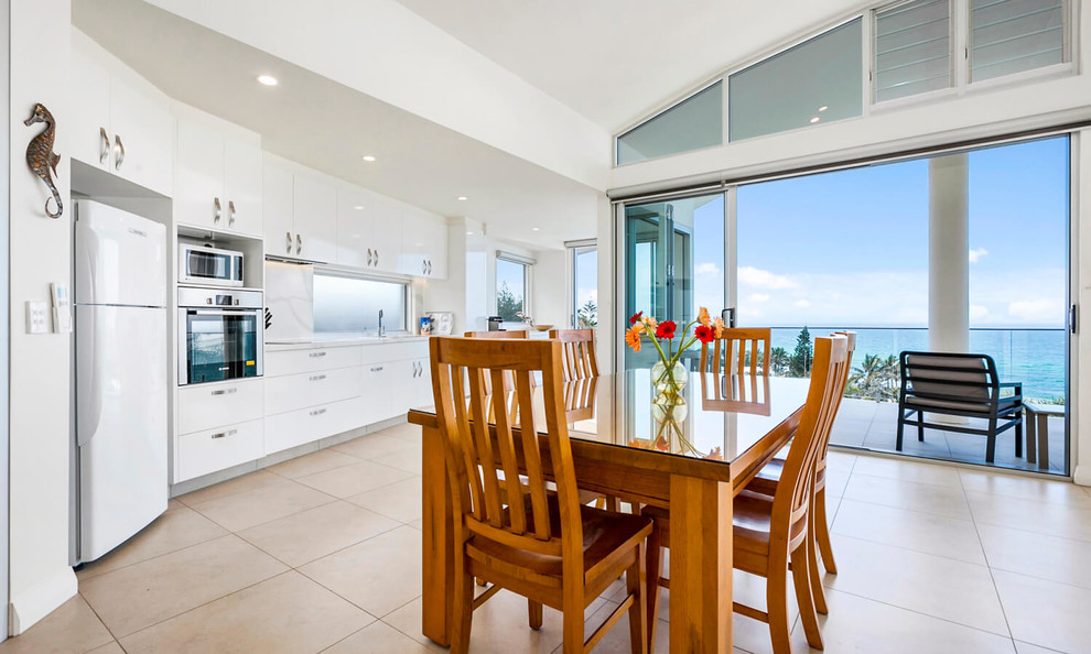 Inspiration for a mid-sized beach style open plan dining in Sunshine Coast with white walls, ceramic floors and beige floor.