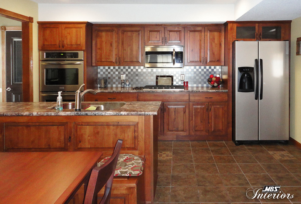 Eat-in kitchen - rustic eat-in kitchen idea with an undermount sink, medium tone wood cabinets, laminate countertops, gray backsplash, metal backsplash and stainless steel appliances
