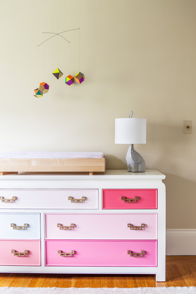 Photo of a transitional nursery for girls in Other with beige walls and light hardwood floors.