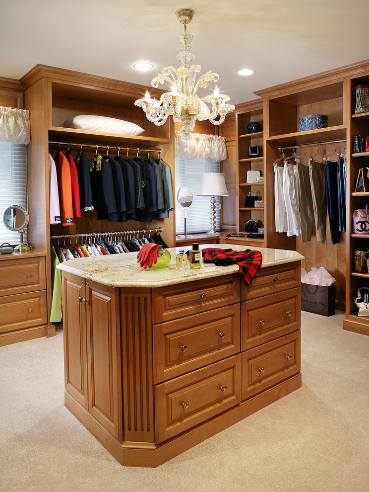This is an example of a mid-sized traditional gender-neutral dressing room in New York with raised-panel cabinets, medium wood cabinets and carpet.