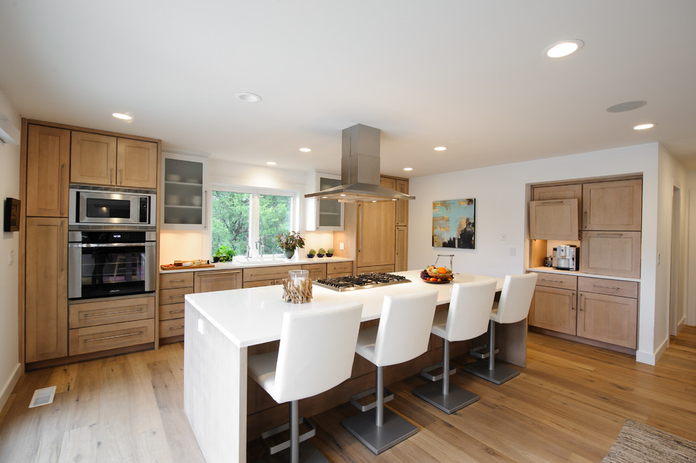 Large contemporary l-shaped eat-in kitchen in Indianapolis with a double-bowl sink, stainless steel appliances, with island, white splashback, shaker cabinets, light wood cabinets, light hardwood floors and brown floor.