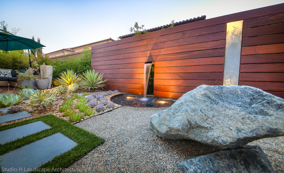 Design ideas for a mid-sized contemporary partial sun xeriscape in Orange County with a water feature and gravel.