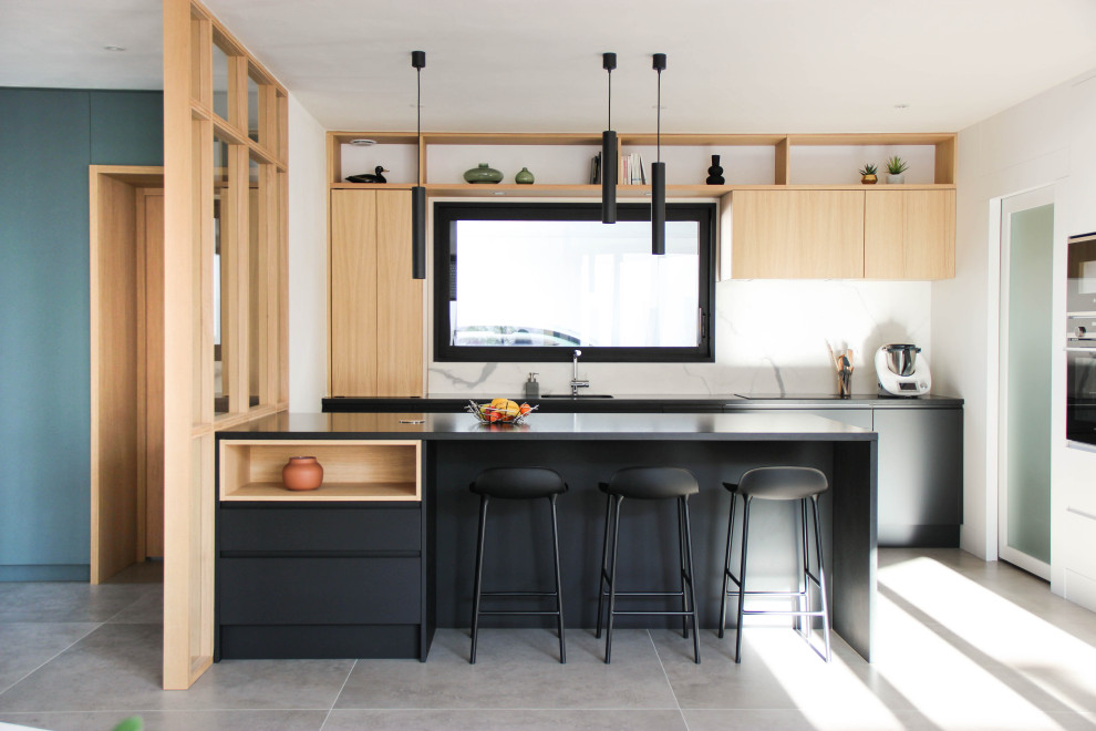 Exemple d'une cuisine ouverte tendance avec un placard à porte affleurante, un plan de travail en granite, une crédence blanche, une crédence en marbre et plan de travail noir.