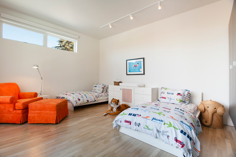 Photo of a contemporary gender-neutral kids' bedroom in Other with white walls and light hardwood floors.