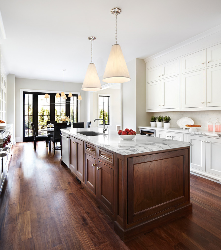 Inspiration for a transitional eat-in kitchen in Toronto with an undermount sink, shaker cabinets, white cabinets, white splashback, dark hardwood floors and with island.