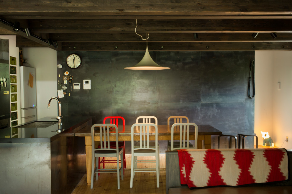 Immagine di una grande sala da pranzo minimalista con pareti bianche, pavimento in legno massello medio, stufa a legna, cornice del camino in metallo, travi a vista e pareti in perlinato
