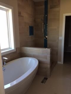 Immagine di una piccola stanza da bagno padronale contemporanea con vasca freestanding, doccia aperta, piastrelle blu, piastrelle di vetro e pareti beige