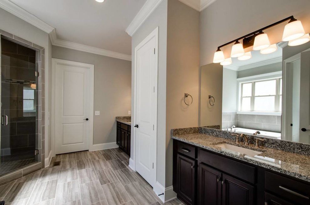 Mid-sized transitional 3/4 gray tile and porcelain tile porcelain tile and gray floor corner shower photo with recessed-panel cabinets, black cabinets, beige walls, an undermount sink, granite countertops and a hinged shower door