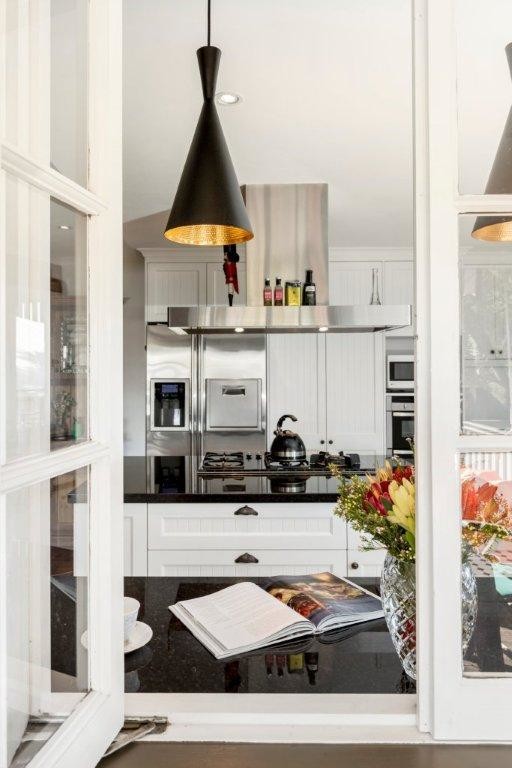 Design ideas for a mid-sized traditional u-shaped eat-in kitchen in Brisbane with a farmhouse sink, recessed-panel cabinets, white cabinets, granite benchtops, white splashback, subway tile splashback, stainless steel appliances, ceramic floors and with island.