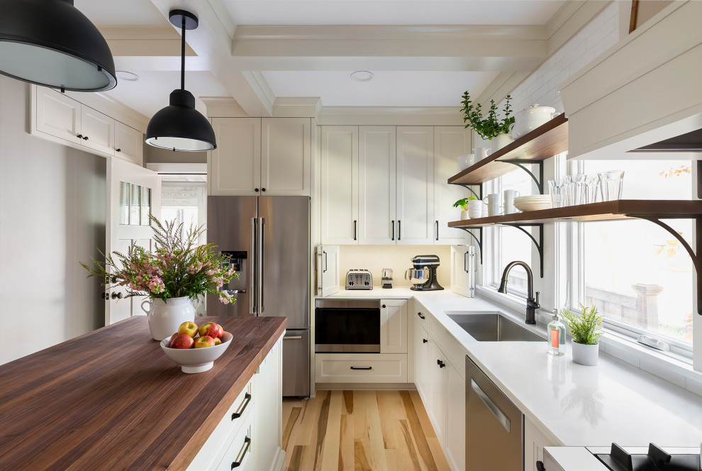 ミネアポリスにある中くらいなトランジショナルスタイルのおしゃれなキッチン (アンダーカウンターシンク、落し込みパネル扉のキャビネット、白いキャビネット、クオーツストーンカウンター、白いキッチンパネル、セラミックタイルのキッチンパネル、シルバーの調理設備、淡色無垢フローリング、茶色い床、白いキッチンカウンター、格子天井) の写真