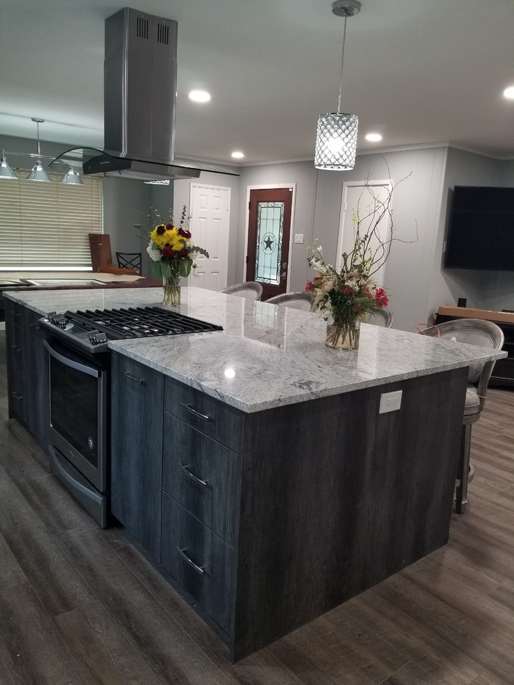 Inspiration for a mid-sized transitional single-wall open plan kitchen in Dallas with an undermount sink, flat-panel cabinets, grey cabinets, blue splashback, stainless steel appliances, with island, brown floor, grey benchtop, granite benchtops, glass tile splashback and laminate floors.