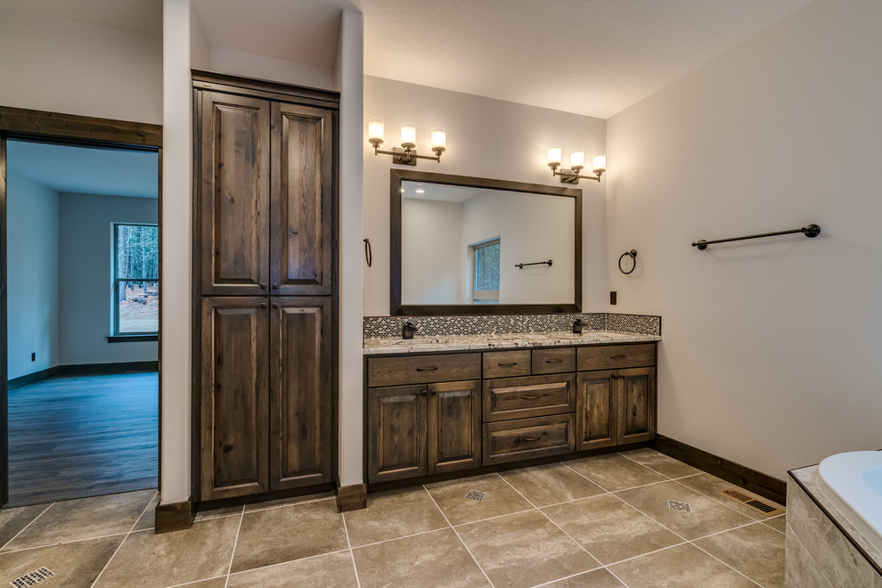 Large mountain style master beige tile and ceramic tile ceramic tile and beige floor corner bathtub photo with raised-panel cabinets, medium tone wood cabinets and an undermount sink