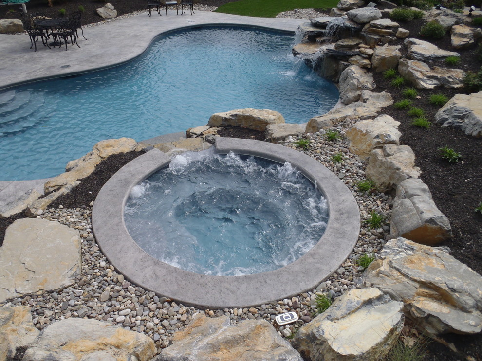 Photo of a traditional backyard custom-shaped natural pool in Philadelphia with stamped concrete and a hot tub.
