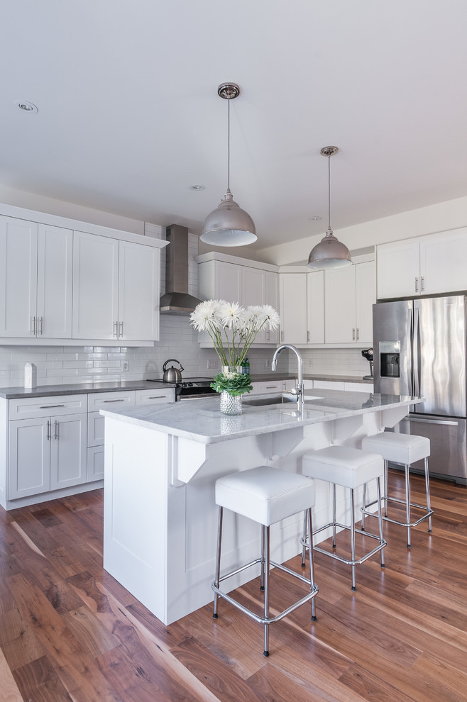 Mid-sized modern l-shaped eat-in kitchen in Toronto with an undermount sink, beaded inset cabinets, white cabinets, white splashback, subway tile splashback, stainless steel appliances, medium hardwood floors and with island.