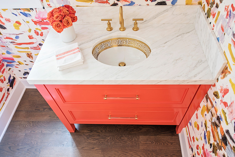 Photo of an eclectic powder room in Austin with orange cabinets and marble benchtops.