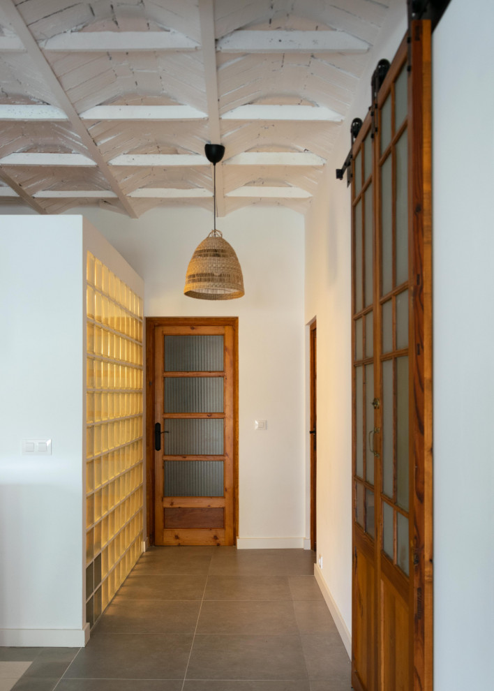 Cette photo montre un petit couloir méditerranéen avec un mur blanc, un sol en carrelage de céramique, un sol gris et un plafond voûté.