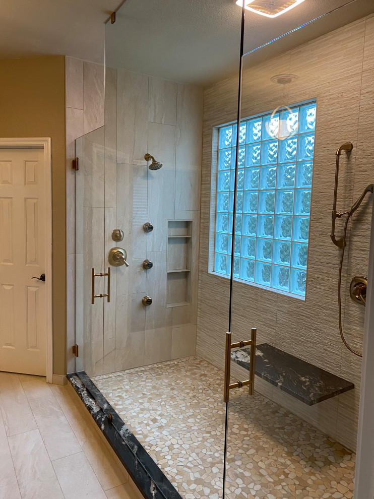 Example of a large trendy master beige tile and porcelain tile porcelain tile, beige floor and double-sink bathroom design in Austin with raised-panel cabinets, medium tone wood cabinets, a two-piece toilet, brown walls, an undermount sink, granite countertops, a hinged shower door, black countertops and a built-in vanity