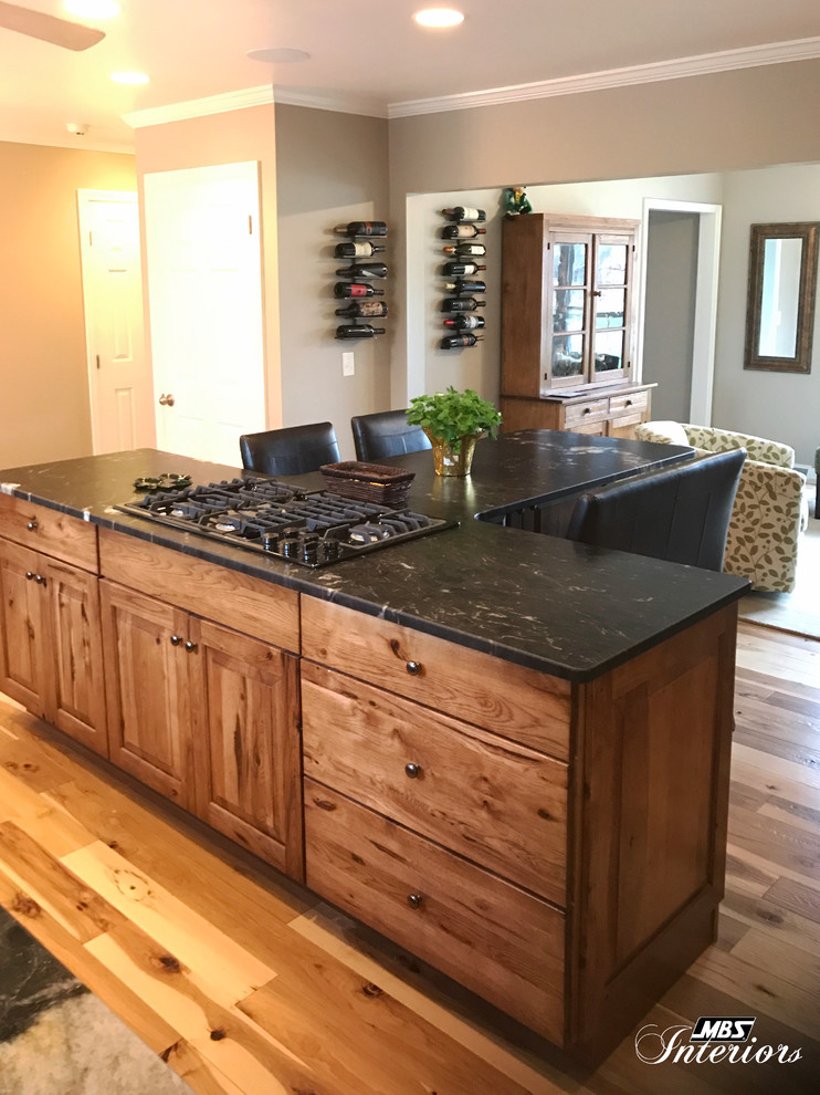 Inspiration for a large rustic l-shaped light wood floor and beige floor eat-in kitchen remodel with an undermount sink, raised-panel cabinets, medium tone wood cabinets, granite countertops, gray backsplash, ceramic backsplash, stainless steel appliances and an island
