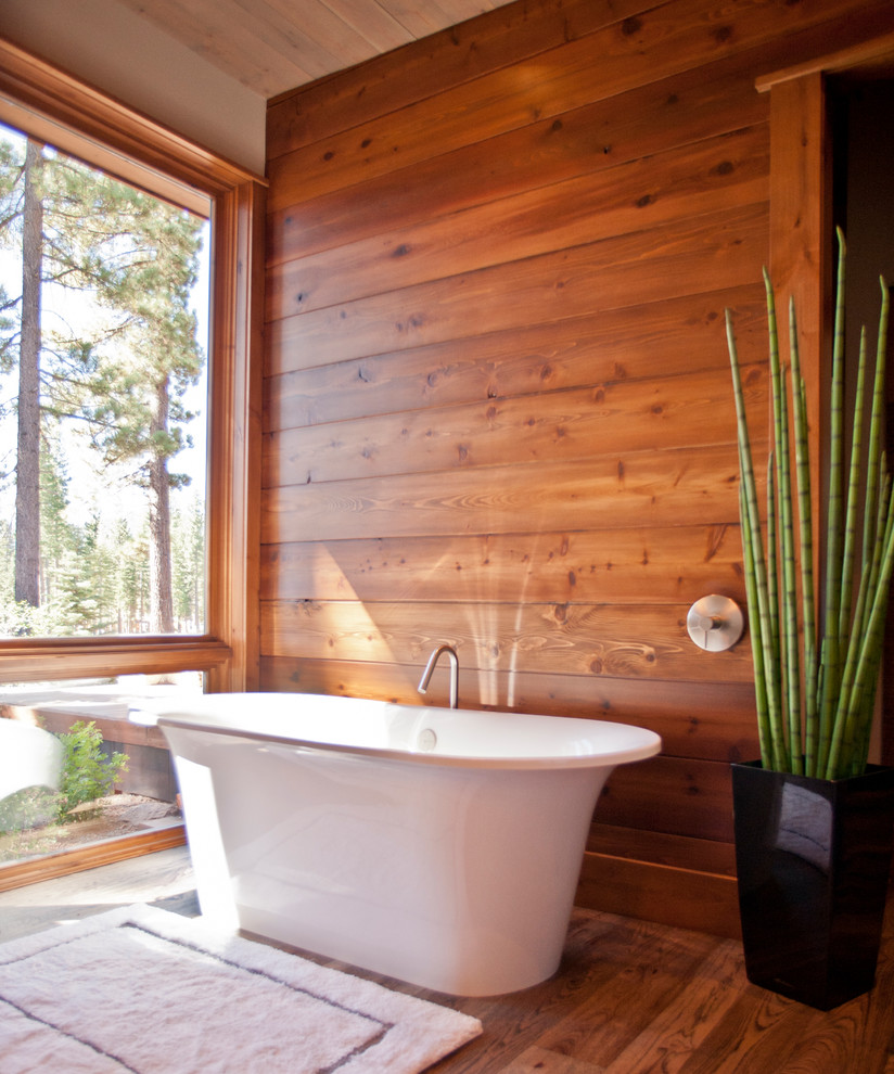 Mountain style medium tone wood floor freestanding bathtub photo in Sacramento with beige walls