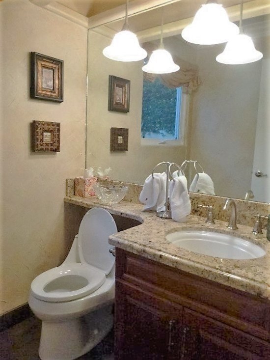 Inspiration for a small mediterranean 3/4 bathroom in Hawaii with raised-panel cabinets, medium wood cabinets, a one-piece toilet, beige walls, terra-cotta floors, an undermount sink and granite benchtops.