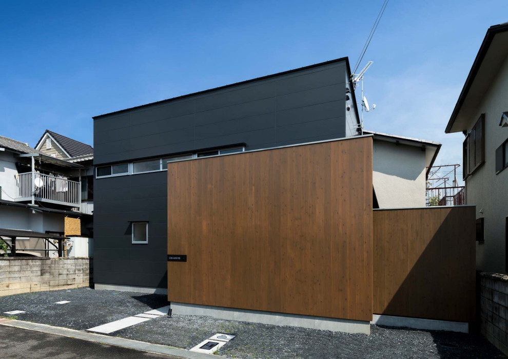 Small scandinavian two-storey black house exterior in Kyoto with concrete fiberboard siding, a shed roof and a metal roof.