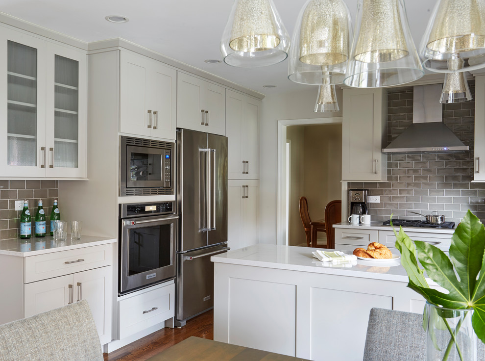 Eat-in kitchen - mid-sized transitional u-shaped medium tone wood floor and brown floor eat-in kitchen idea in Chicago with an undermount sink, shaker cabinets, white cabinets, quartz countertops, gray backsplash, subway tile backsplash, paneled appliances, a peninsula and white countertops