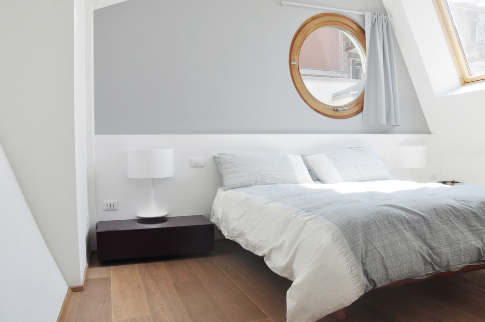 This is an example of a modern master bedroom in Bologna with grey walls and light hardwood floors.