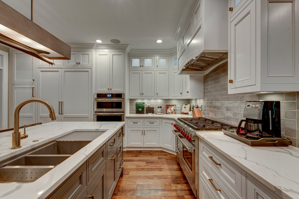 Large transitional u-shaped open plan kitchen in Raleigh with beaded inset cabinets, white cabinets, grey splashback, panelled appliances, dark hardwood floors, with island, a triple-bowl sink, marble benchtops and subway tile splashback.