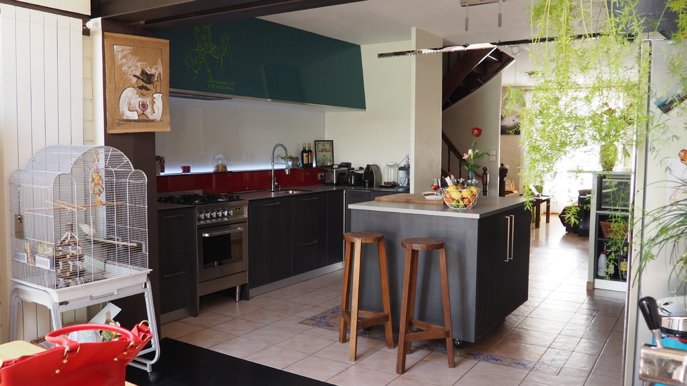 Photo of a large modern galley open plan kitchen in Nantes with a single-bowl sink, flat-panel cabinets, dark wood cabinets, laminate benchtops, red splashback, glass sheet splashback, stainless steel appliances, ceramic floors, with island and pink floor.