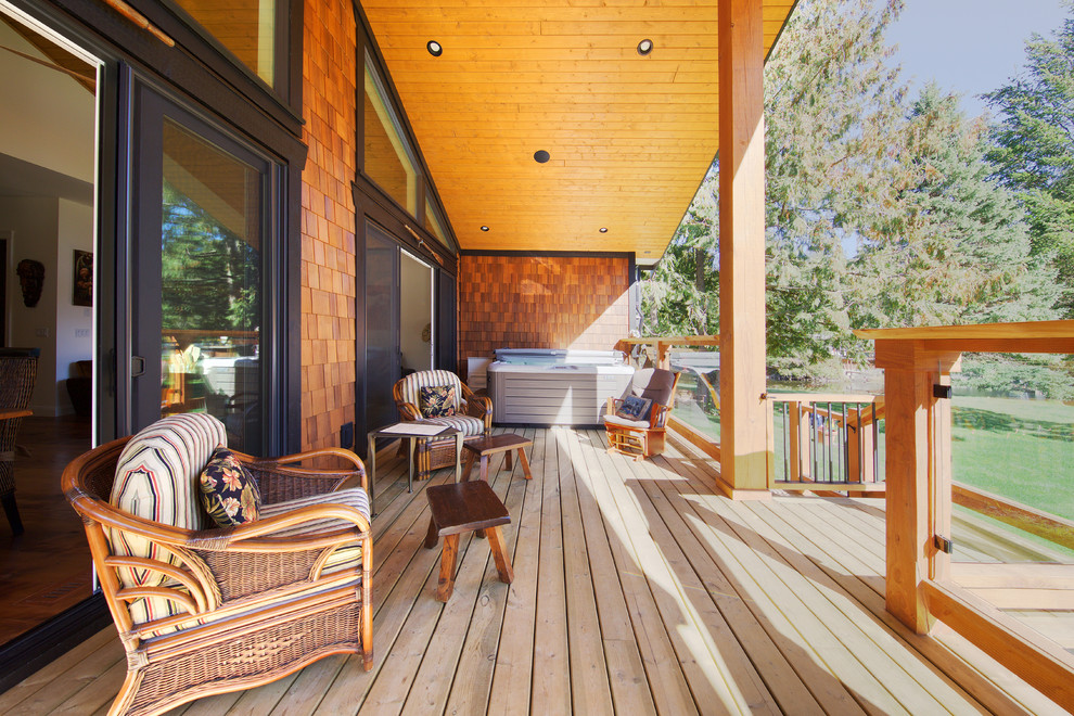 Example of a mid-sized mountain style backyard water fountain deck design in Vancouver with a roof extension