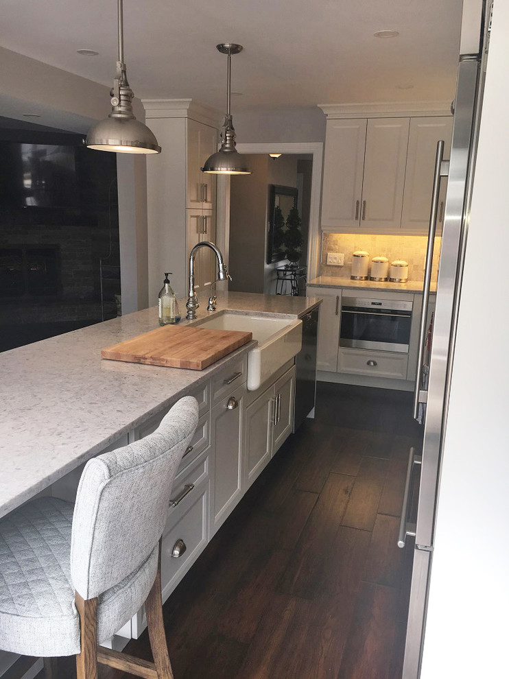 Eat-in kitchen - transitional l-shaped brown floor eat-in kitchen idea with a farmhouse sink, white cabinets, quartz countertops, stainless steel appliances, an island and white countertops