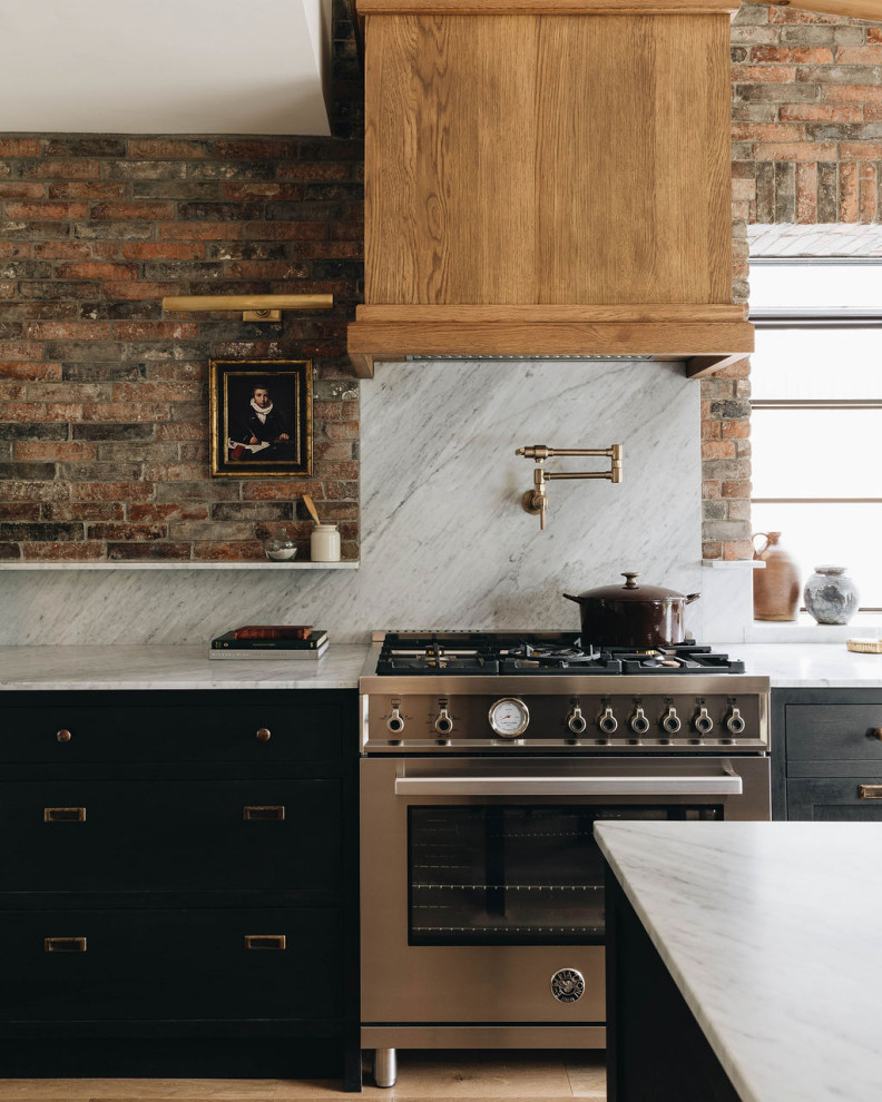 Foto di una cucina design con ante nere, paraspruzzi bianco, elettrodomestici in acciaio inossidabile, parquet chiaro, pavimento marrone, top bianco e travi a vista