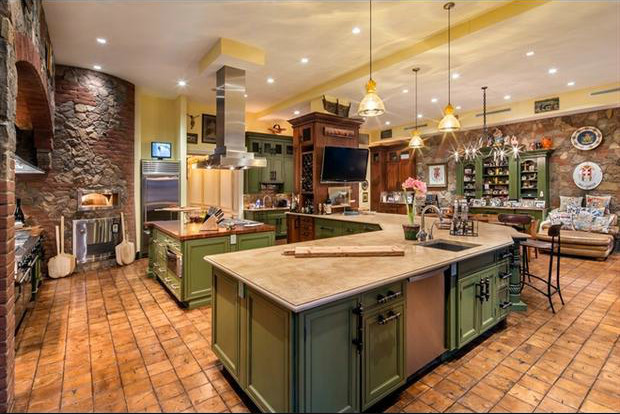 Photo of an expansive country l-shaped open plan kitchen in Chicago with an undermount sink, recessed-panel cabinets, green cabinets, soapstone benchtops, brown splashback, brick splashback, stainless steel appliances, terra-cotta floors, with island and beige floor.