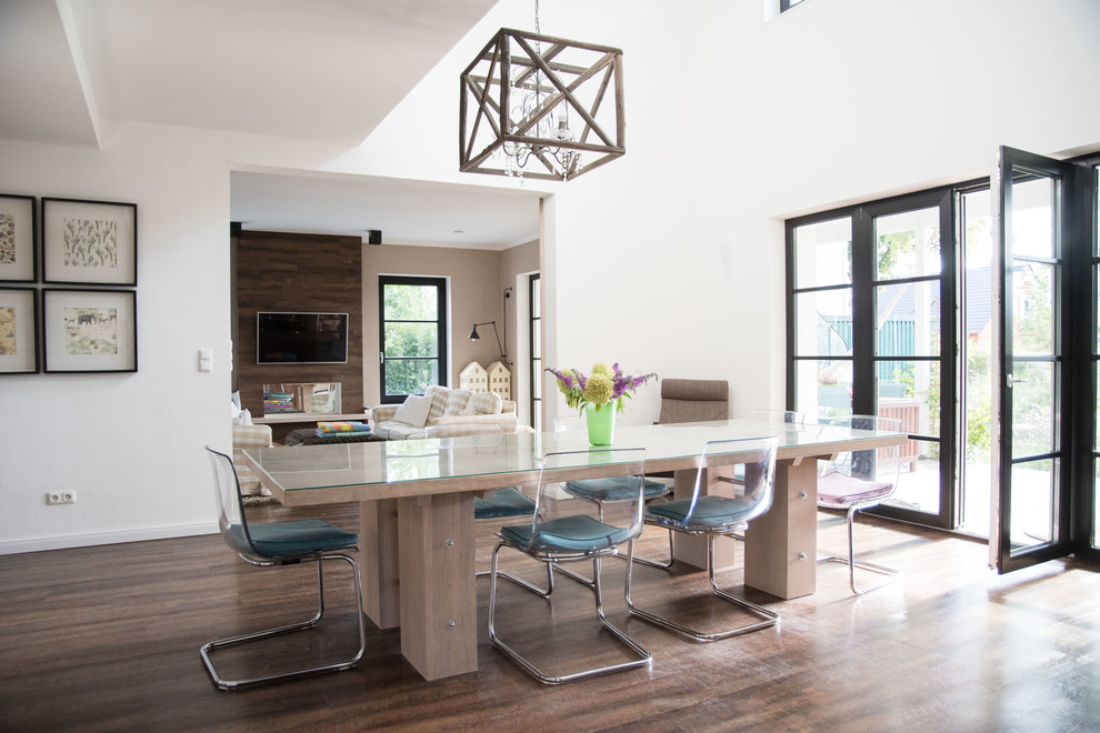 Photo of a mid-sized country open plan dining in Berlin with white walls and dark hardwood floors.