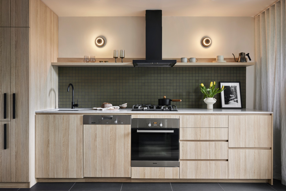 Small scandinavian single-wall open plan kitchen in Melbourne with an undermount sink, flat-panel cabinets, light wood cabinets, quartz benchtops, green splashback, ceramic splashback, black appliances, light hardwood floors, no island, yellow floor and grey benchtop.