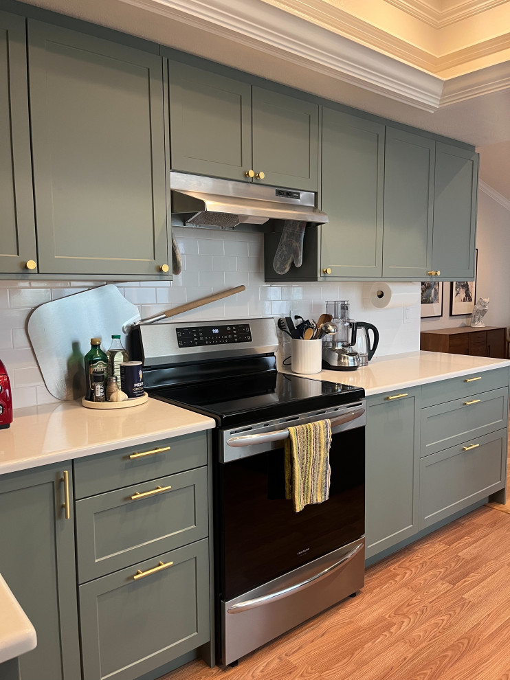 Mid-sized transitional u-shaped eat-in kitchen in Orange County with an undermount sink, shaker cabinets, green cabinets, yellow splashback, subway tile splashback, stainless steel appliances, medium hardwood floors, a peninsula, brown floor, white benchtop and recessed.