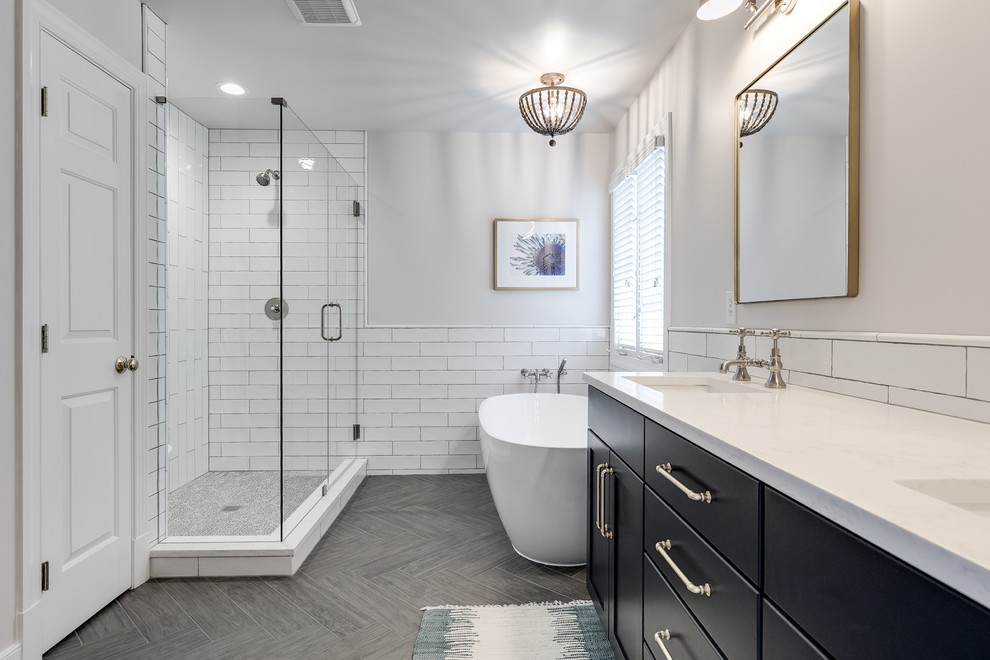 Photo of a large contemporary master bathroom in Richmond with recessed-panel cabinets, blue cabinets, a freestanding tub, a corner shower, a two-piece toilet, white tile, subway tile, white walls, porcelain floors, an undermount sink, engineered quartz benchtops, grey floor, a hinged shower door and white benchtops.