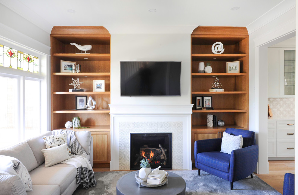 This is an example of a mid-sized transitional formal open concept living room in Vancouver with grey walls, a standard fireplace, a tile fireplace surround, a wall-mounted tv and medium hardwood floors.