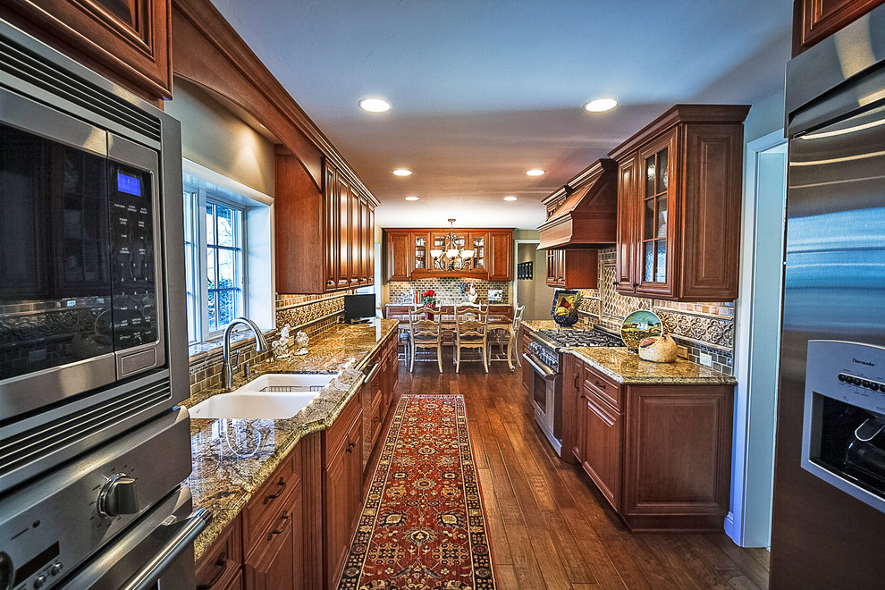 Photo of a mid-sized traditional u-shaped eat-in kitchen in Sacramento with an undermount sink, raised-panel cabinets, medium wood cabinets, granite benchtops, porcelain splashback, stainless steel appliances, medium hardwood floors, no island, brown splashback and brown floor.