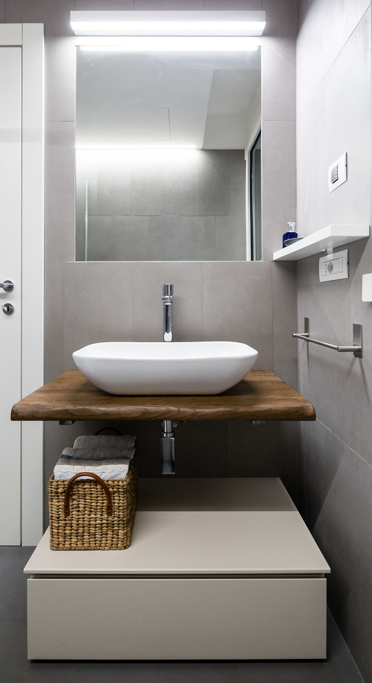 Photo of a scandinavian 3/4 bathroom in Milan with flat-panel cabinets, beige cabinets, gray tile, a vessel sink, wood benchtops, grey floor and brown benchtops.