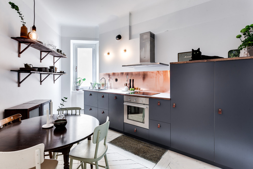 This is an example of a large scandinavian single-wall eat-in kitchen in Stockholm with flat-panel cabinets, black cabinets, metallic splashback, stainless steel appliances, painted wood floors and no island.