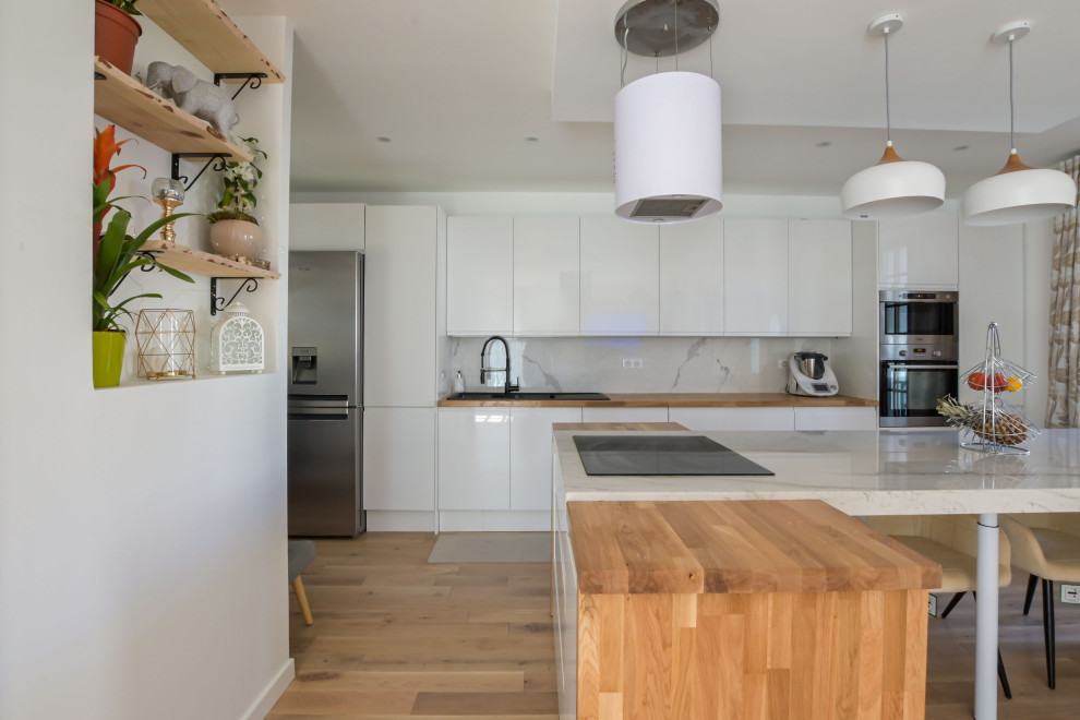 Inspiration för ett stort funkis brun linjärt brunt kök med öppen planlösning, med en integrerad diskho, släta luckor, vita skåp, träbänkskiva, vitt stänkskydd, stänkskydd i marmor, integrerade vitvaror, ljust trägolv, en köksö och brunt golv