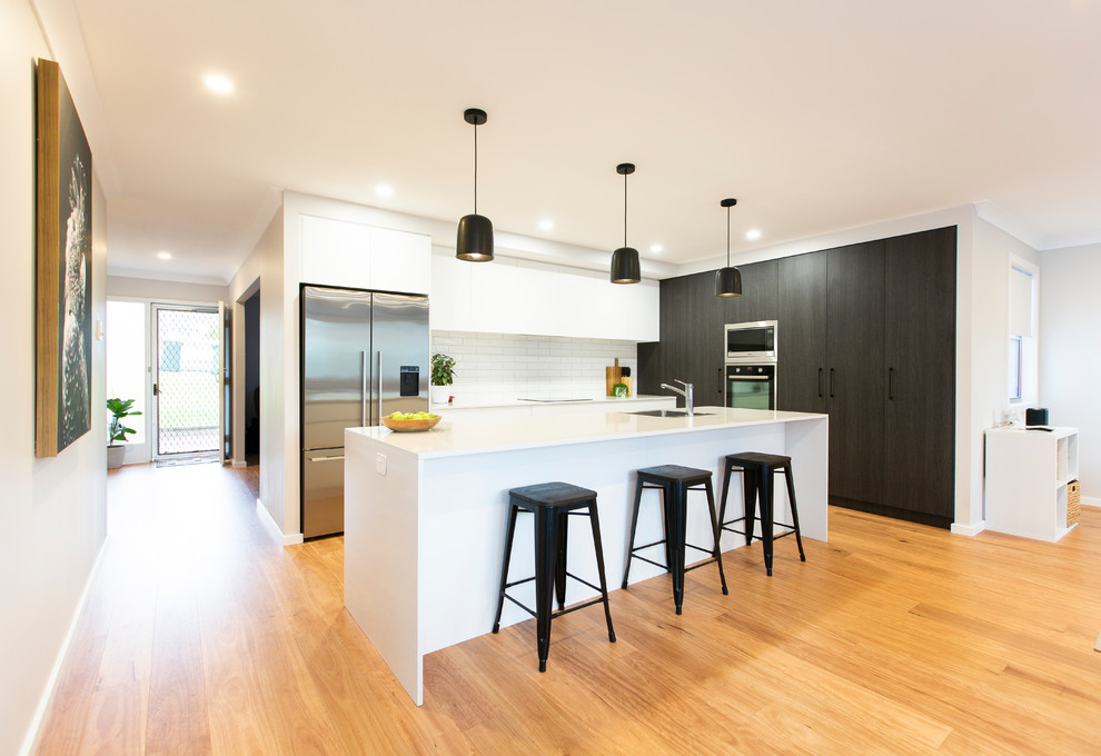 Design ideas for a large contemporary galley eat-in kitchen in Newcastle - Maitland with flat-panel cabinets, white cabinets, quartz benchtops, white splashback, subway tile splashback and with island.