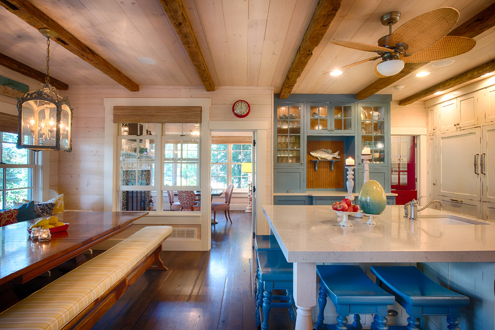 Mid-sized beach style l-shaped eat-in kitchen in Minneapolis with shaker cabinets, distressed cabinets, with island, white splashback, ceramic splashback, a farmhouse sink, quartzite benchtops, stainless steel appliances and medium hardwood floors.