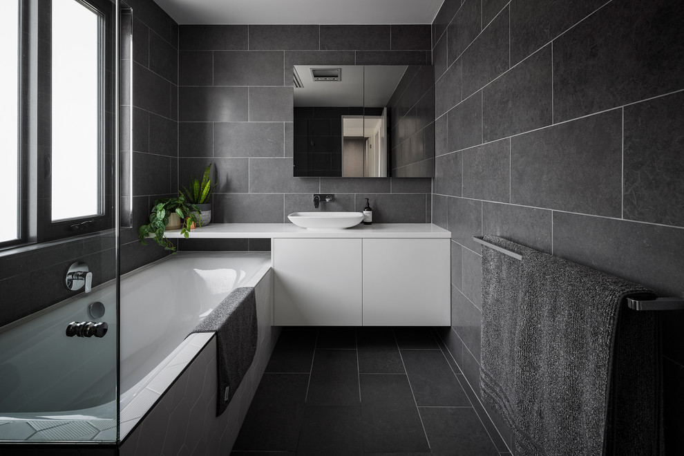 Inspiration for a small contemporary bathroom in Canberra - Queanbeyan with flat-panel cabinets, white cabinets, black tile, porcelain tile, black walls, porcelain floors, a vessel sink, engineered quartz benchtops, black floor, white benchtops and an undermount tub.