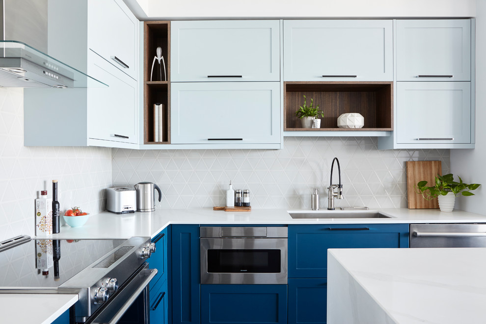 Photo of a mid-sized modern l-shaped eat-in kitchen in Toronto with a single-bowl sink, shaker cabinets, blue cabinets, quartz benchtops, beige splashback, ceramic splashback, stainless steel appliances, dark hardwood floors, with island, brown floor and white benchtop.