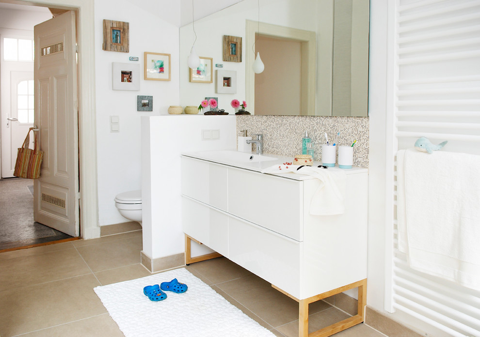 Skandinavisches Badezimmer mit beigem Boden, flächenbündigen Schrankfronten, weißen Schränken, beigen Fliesen, Mosaikfliesen, weißer Wandfarbe, weißer Waschtischplatte, Einzelwaschbecken und freistehendem Waschtisch in Hamburg