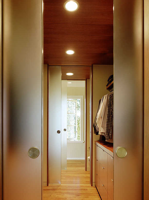 This is an example of a large modern gender-neutral dressing room in San Francisco with flat-panel cabinets, medium wood cabinets and light hardwood floors.
