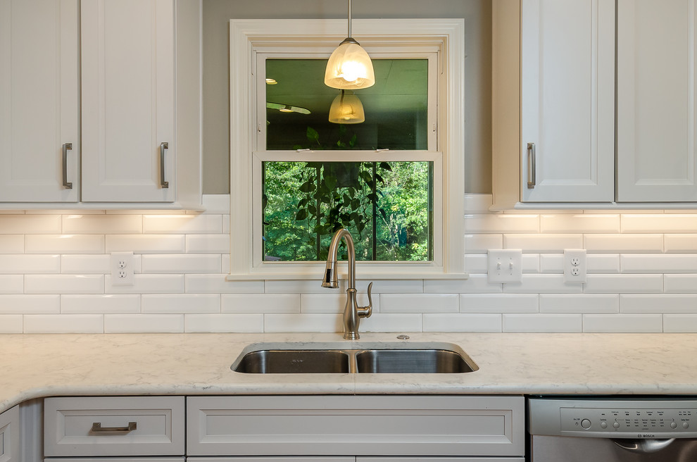 This is an example of a small transitional l-shaped eat-in kitchen in Other with a double-bowl sink, shaker cabinets, grey cabinets, quartz benchtops, white splashback, subway tile splashback, stainless steel appliances, medium hardwood floors, no island, brown floor and white benchtop.