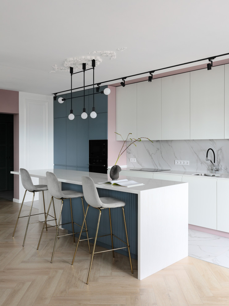 This is an example of a mid-sized contemporary single-wall eat-in kitchen in Saint Petersburg with a single-bowl sink, flat-panel cabinets, white cabinets, solid surface benchtops, white splashback, medium hardwood floors, with island, brown floor and white benchtop.